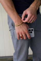 man wearing gold bracelets and red gemstone ring
