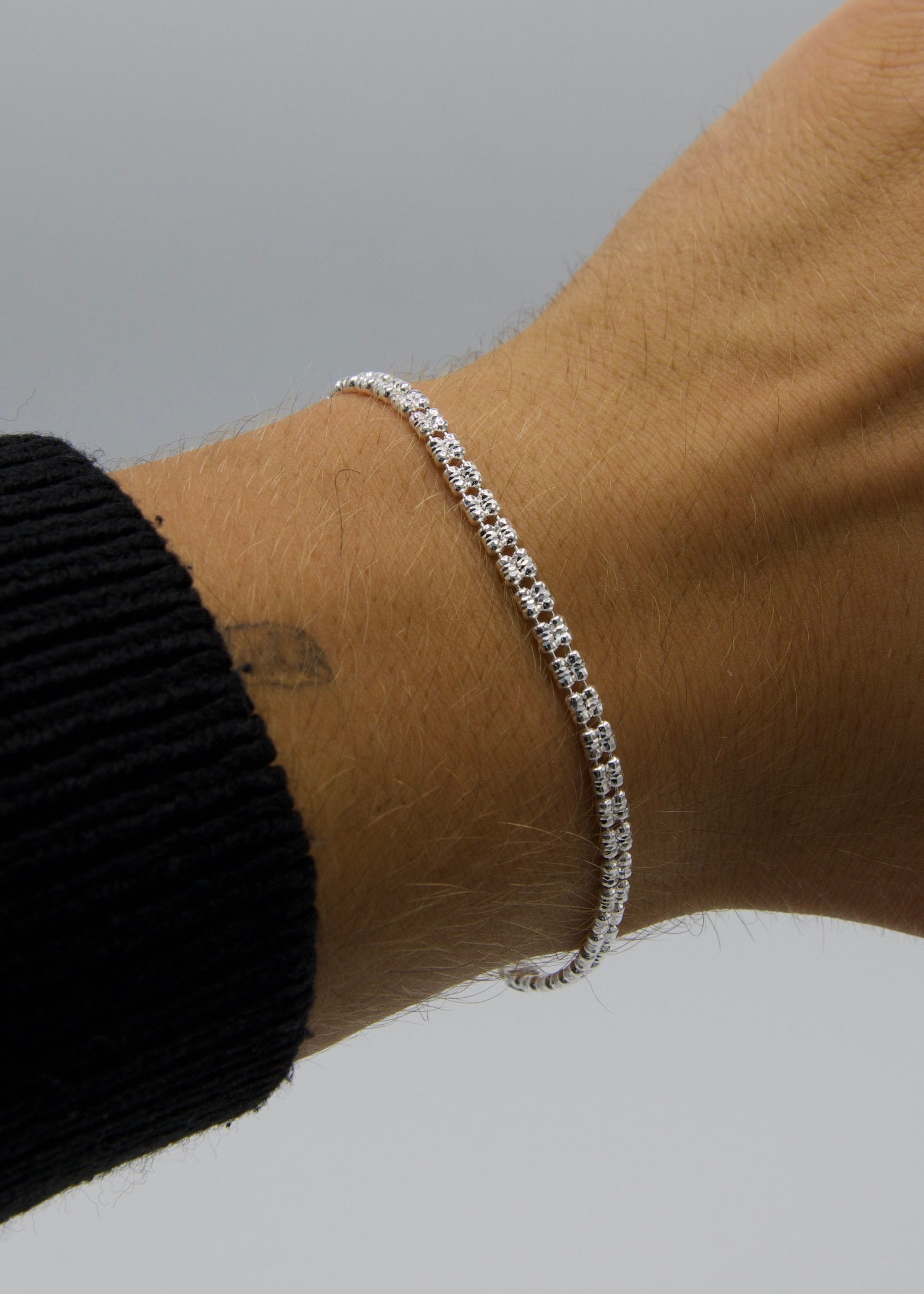 Silver bracelet on a wrist with a plain background