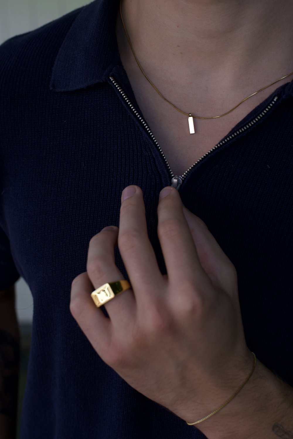 man wearing gold slated ring and gold pendant necklace