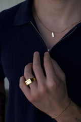 man wearing gold slated ring and gold pendant necklace